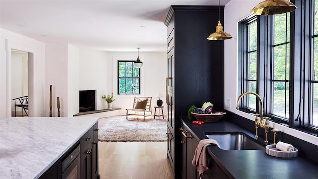 kitchen with hanging light fixtures, sink, and light hardwood / wood-style floors