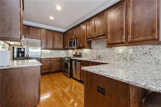 kitchen with sink, light hardwood / wood-style floors, light stone counters, and stainless steel appliances