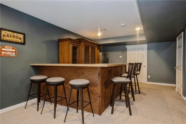 kitchen with a kitchen bar, light colored carpet, and kitchen peninsula