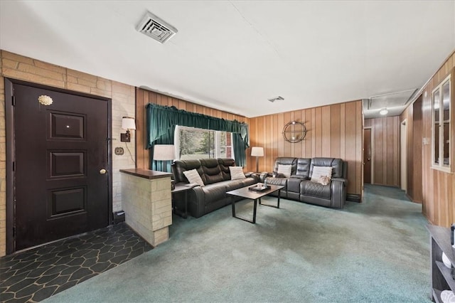 living room with dark colored carpet and wood walls