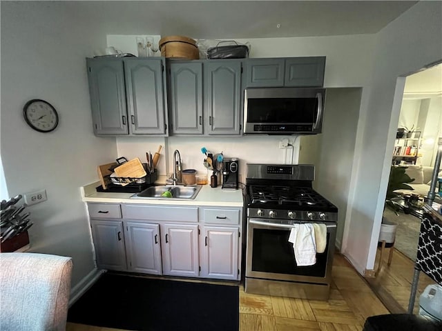 kitchen with gray cabinetry, sink, and stainless steel appliances