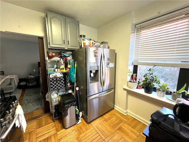 kitchen with gas stove, stainless steel fridge with ice dispenser, and light parquet floors