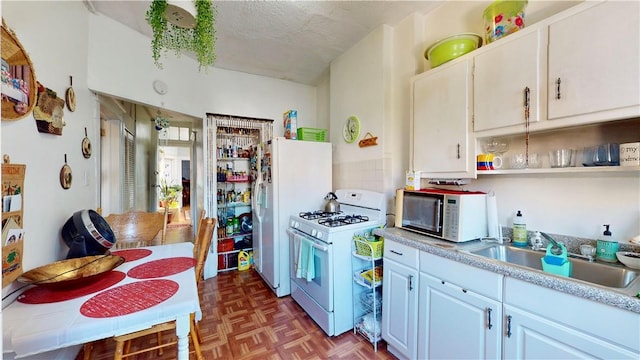 kitchen featuring a textured ceiling, white appliances, dark parquet floors, sink, and white cabinets