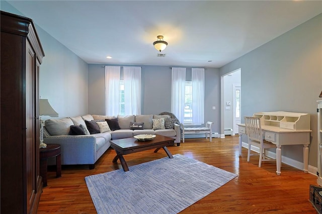 living room with baseboard heating and dark wood-type flooring