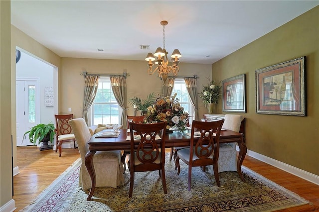 dining space with light hardwood / wood-style flooring and a chandelier