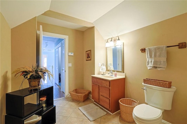 bathroom with tile patterned flooring, vanity, vaulted ceiling, and toilet