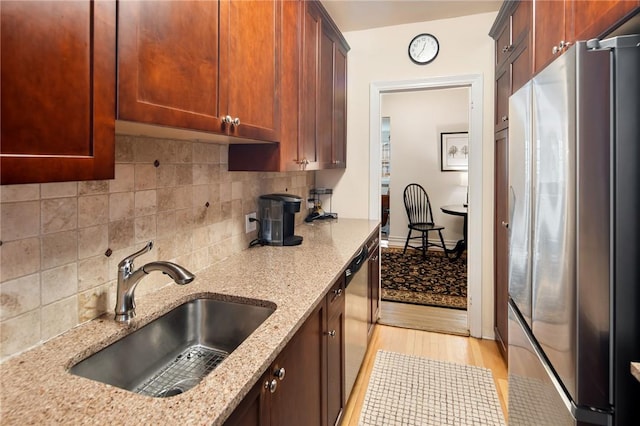 kitchen featuring light stone countertops, stainless steel appliances, light hardwood / wood-style floors, and sink