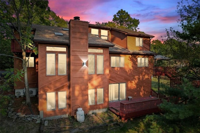 back house at dusk featuring a wooden deck