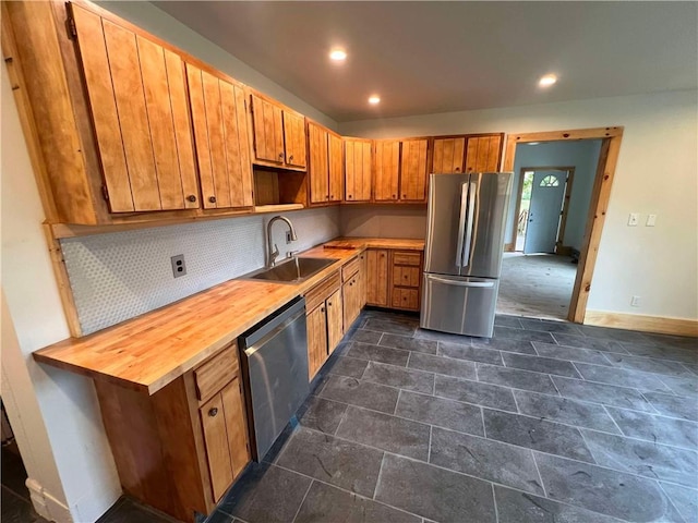 kitchen with butcher block countertops, backsplash, sink, and stainless steel appliances