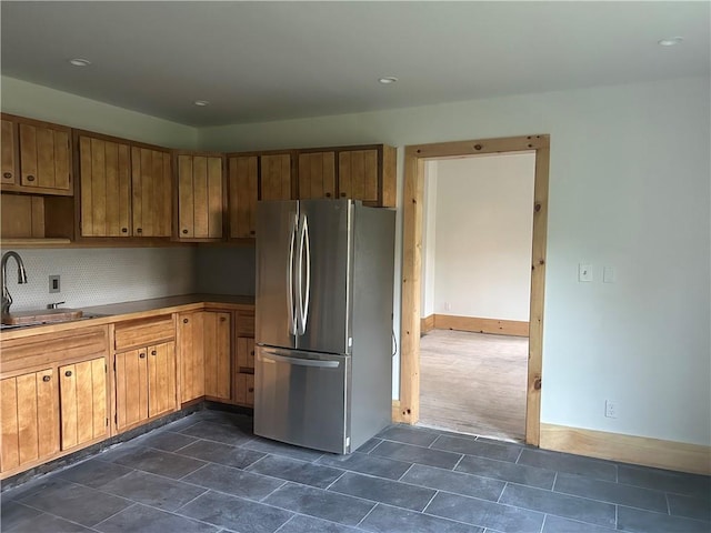 kitchen with dark colored carpet, stainless steel fridge, sink, and tasteful backsplash