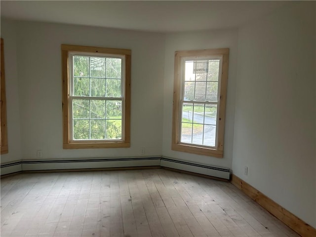 empty room featuring a baseboard radiator and light wood-type flooring