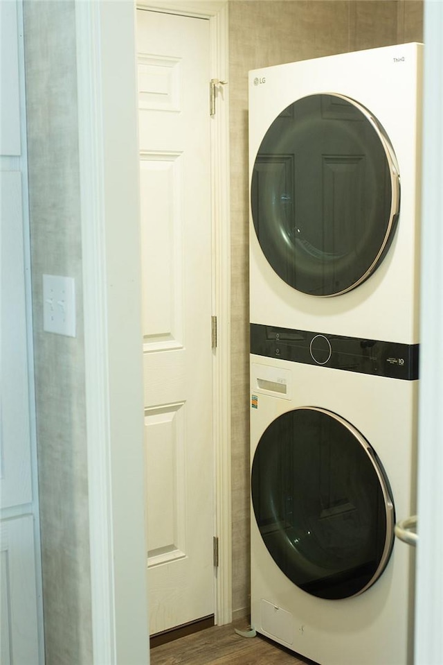 laundry area with dark hardwood / wood-style flooring and stacked washer and clothes dryer