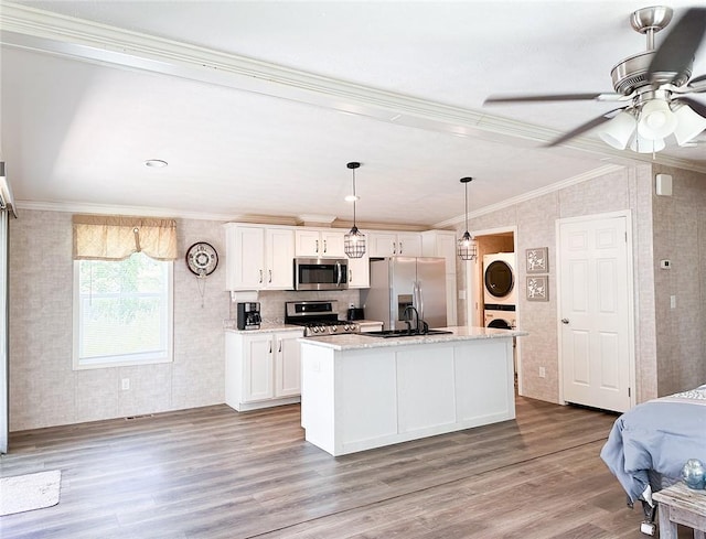 kitchen featuring white cabinetry, stacked washing maching and dryer, light hardwood / wood-style flooring, an island with sink, and appliances with stainless steel finishes