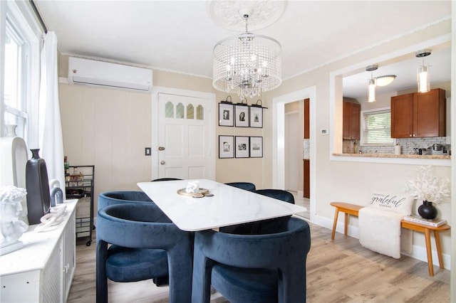 dining room featuring light wood-type flooring, an AC wall unit, crown molding, and an inviting chandelier