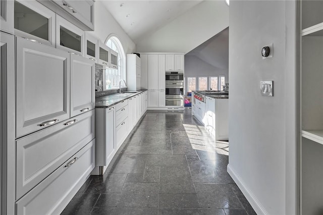 kitchen featuring white cabinets, a healthy amount of sunlight, and vaulted ceiling