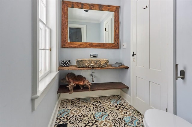 bathroom with tile patterned floors, toilet, sink, and ornamental molding