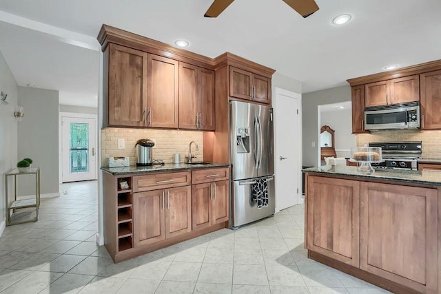 kitchen featuring appliances with stainless steel finishes, sink, tasteful backsplash, and dark stone countertops