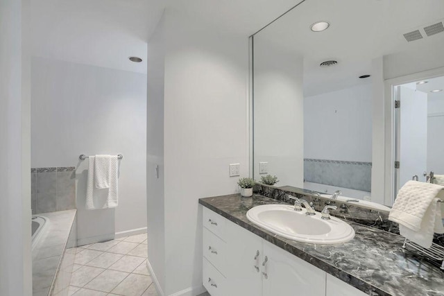 bathroom featuring tile patterned flooring, vanity, and tiled tub