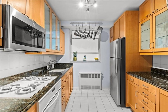 2575 Palisade Ave Unit 2G, Bronx, NY 10463 - kitchen with appliances with stainless steel finishes, radiator heating unit, a sink, light tile patterned floors, and dark stone counters