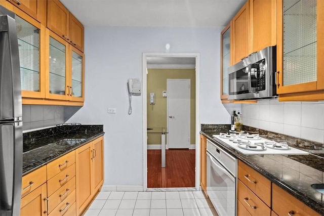 2575 Palisade Ave Unit 2G, Bronx, NY 10463 - kitchen featuring stainless steel appliances, backsplash, baseboards, light tile patterned floors, and glass insert cabinets