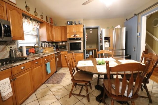 kitchen featuring backsplash, sink, light tile patterned floors, and stainless steel appliances