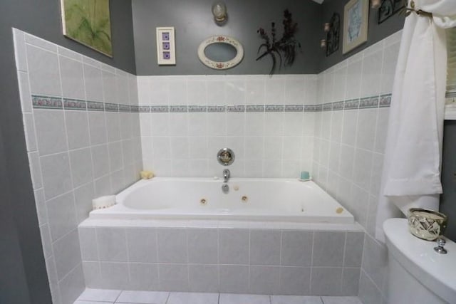 bathroom with tile patterned floors, a relaxing tiled tub, toilet, and tile walls