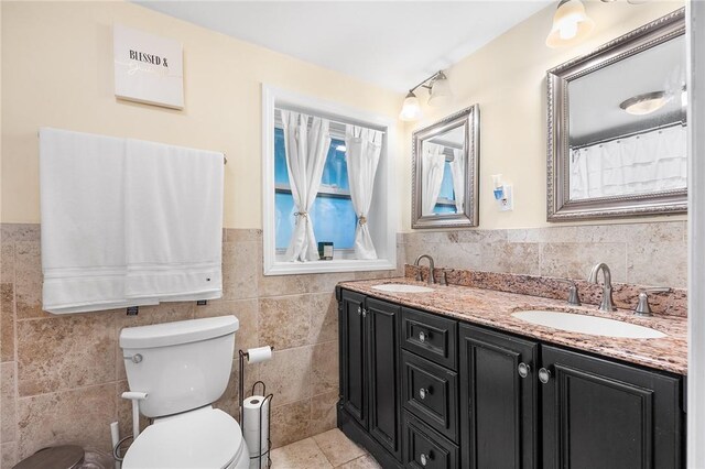 bathroom with tile patterned floors, vanity, toilet, and tile walls