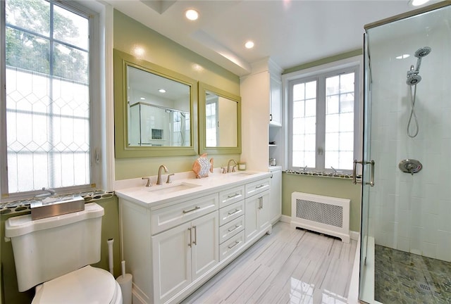 bathroom featuring radiator, vanity, a shower with door, wood-type flooring, and toilet