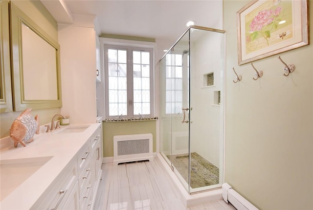 bathroom featuring vanity, baseboard heating, radiator, and a shower with shower door