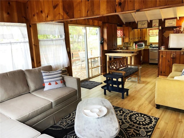 living room featuring light wood-type flooring, lofted ceiling, and wooden walls