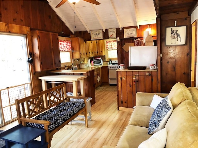 kitchen with wood walls, vaulted ceiling with beams, light hardwood / wood-style floors, and white range with gas cooktop