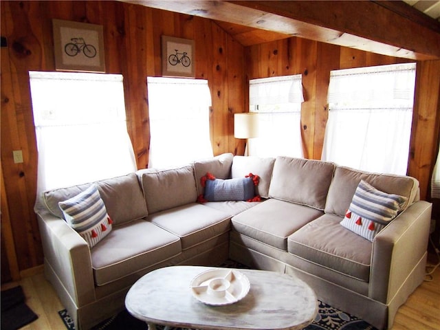 living room with vaulted ceiling with beams, wood walls, plenty of natural light, and light wood-type flooring