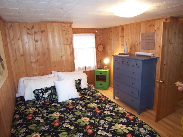 bedroom with light hardwood / wood-style flooring and wood walls