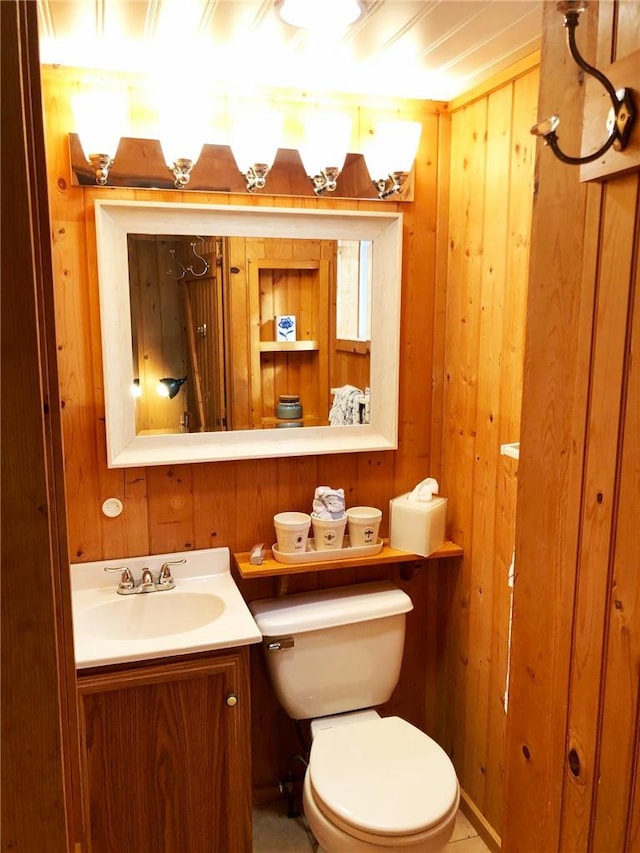 bathroom with wood walls, vanity, and toilet