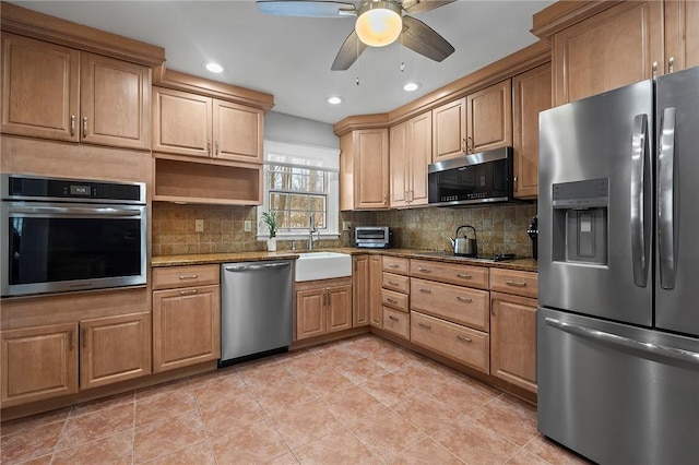 kitchen featuring sink, decorative backsplash, ceiling fan, light stone counters, and stainless steel appliances