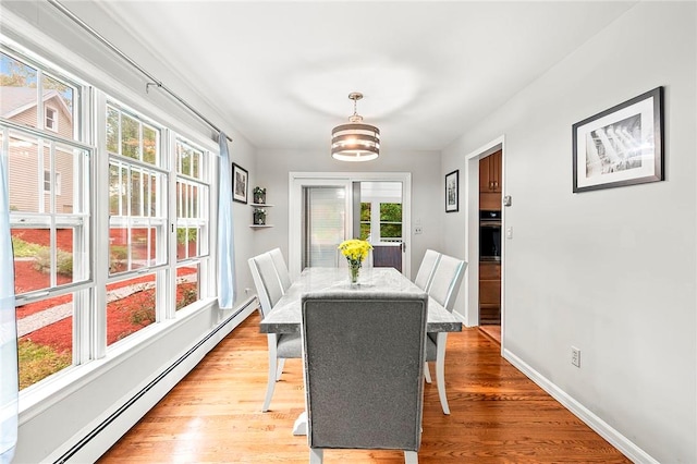 dining area featuring light hardwood / wood-style flooring, a baseboard heating unit, and a notable chandelier