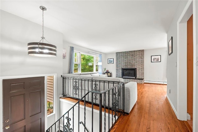 hall featuring hardwood / wood-style floors, a chandelier, and a baseboard heating unit