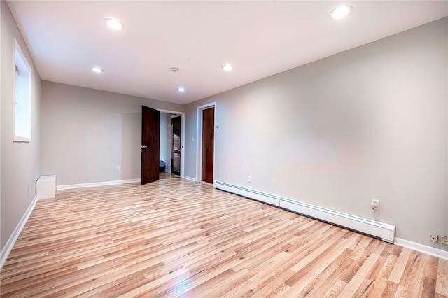 empty room featuring baseboard heating and light hardwood / wood-style flooring