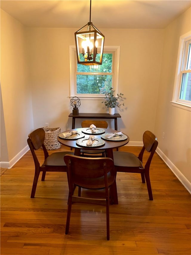 dining area with a wealth of natural light, wood-type flooring, and a notable chandelier