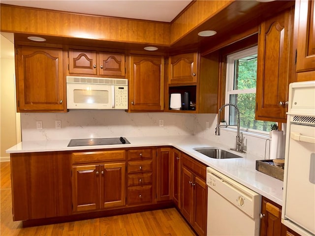 kitchen with tasteful backsplash, sink, light hardwood / wood-style floors, and white appliances