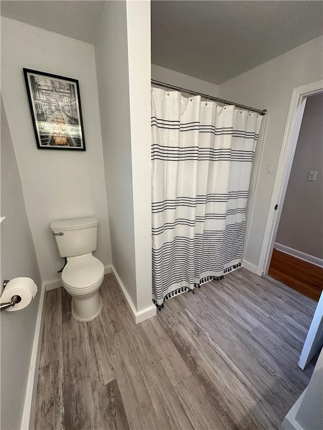 bathroom featuring a shower with curtain, hardwood / wood-style floors, and toilet