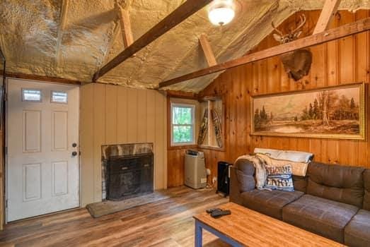 living room with lofted ceiling with beams, wood-type flooring, and wooden walls