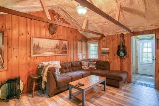 living room with lofted ceiling with beams, wood-type flooring, and wood walls