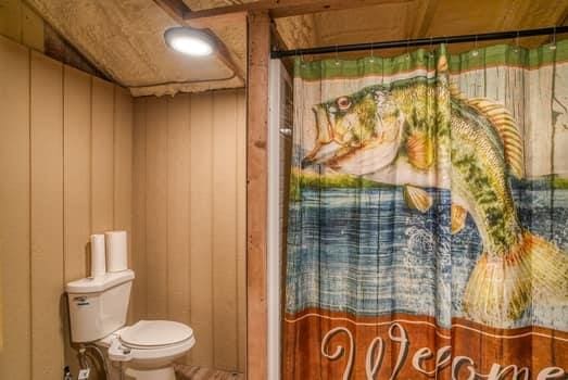 bathroom featuring a shower with curtain, wood walls, and toilet