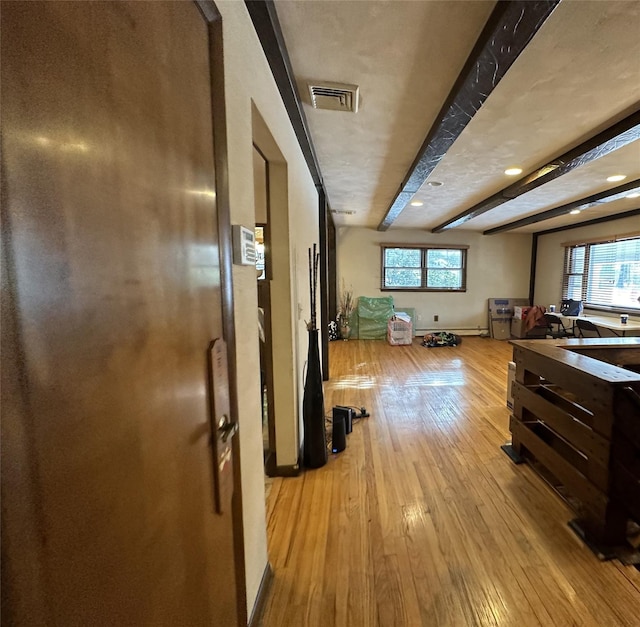 hallway featuring beam ceiling, light hardwood / wood-style flooring, and a healthy amount of sunlight