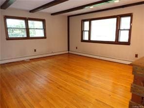 empty room featuring beam ceiling, a baseboard radiator, and light hardwood / wood-style flooring