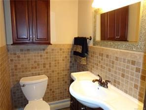 bathroom with vanity, toilet, and tile walls