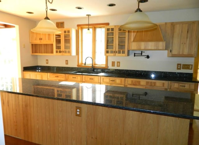 kitchen featuring dark stone countertops, sink, and hanging light fixtures