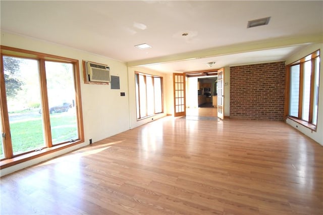 unfurnished room featuring light hardwood / wood-style flooring, a wall mounted AC, and a healthy amount of sunlight