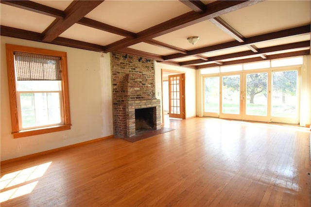 unfurnished living room with beamed ceiling, light hardwood / wood-style floors, a brick fireplace, and coffered ceiling